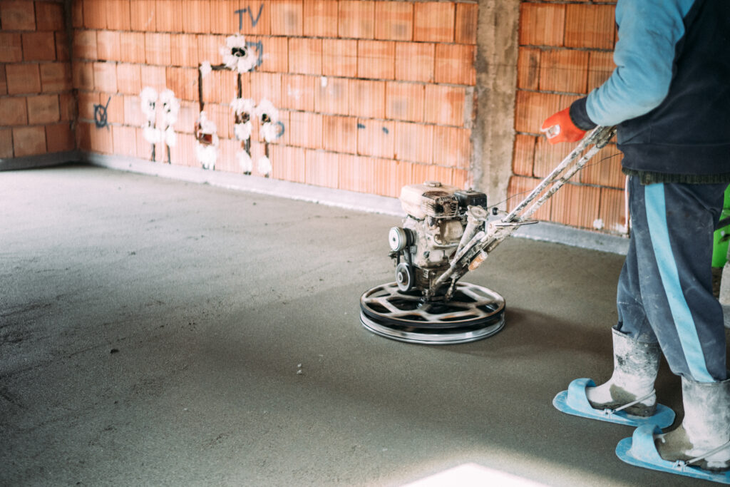 Construction worker finishes concrete screed with power trowel machine
