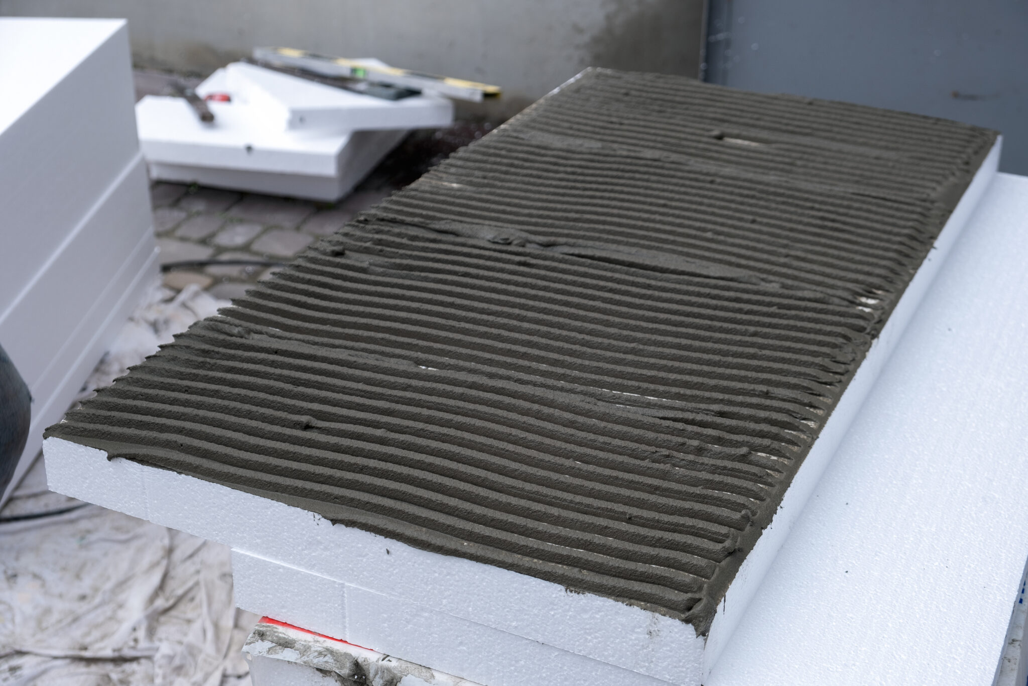 Installation of styrofoam insulation sheets on house facade wall for thermal protection.