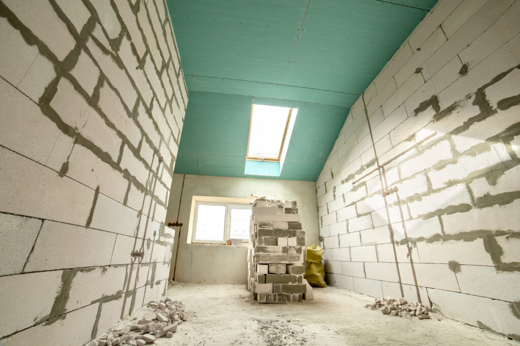 Interior of an apartment room with bare walls and ceiling under construction.